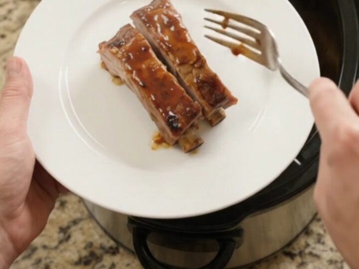Slow cooker with glazed spare ribs and apples, bubbling sauce, high angle