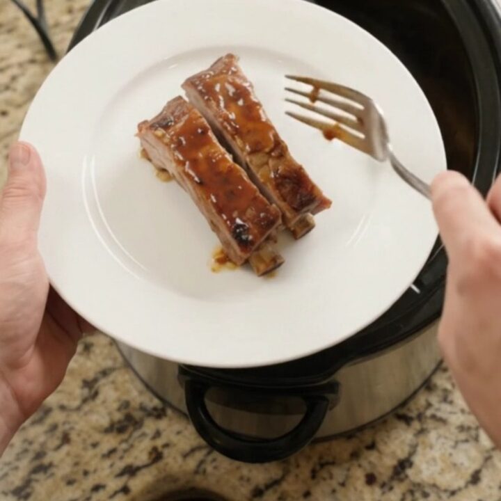 Slow cooker with glazed spare ribs and apples, bubbling sauce, high angle