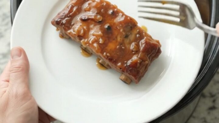 Slow cooker spare ribs glazed with maple bourbon BBQ sauce, topped with braised apple slices