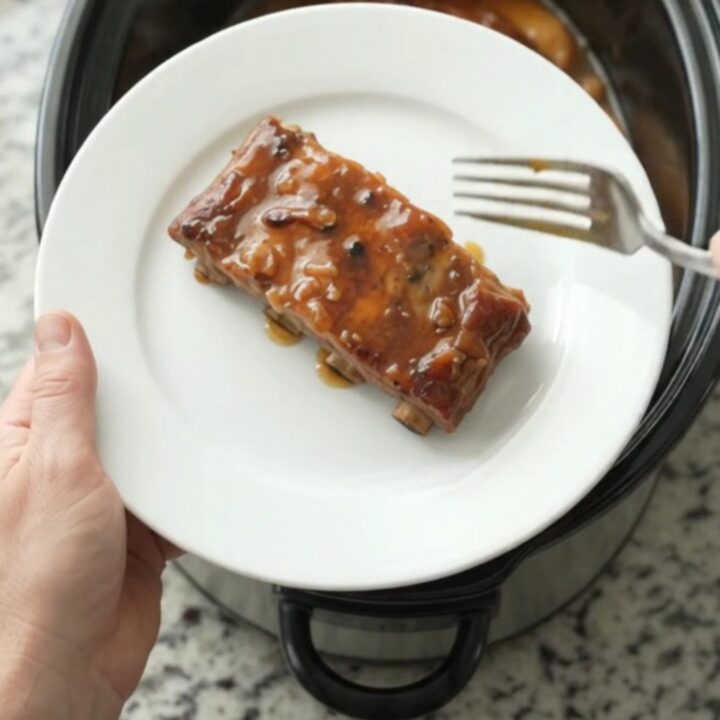 Slow cooker spare ribs glazed with maple bourbon BBQ sauce, topped with braised apple slices