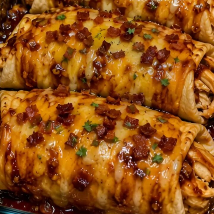 Four golden-brown honey butter BBQ chicken wraps in a glass baking dish with visible melted cheese pull.