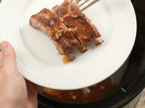 A slow cooker filled with glazed spare ribs and caramelized pineapple rings