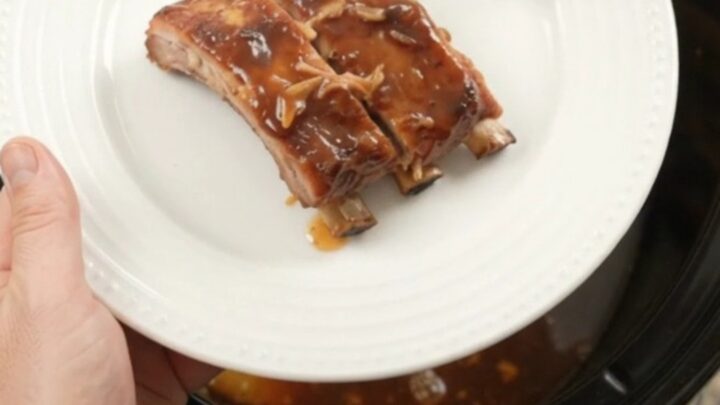 A slow cooker filled with glazed spare ribs and caramelized pineapple rings