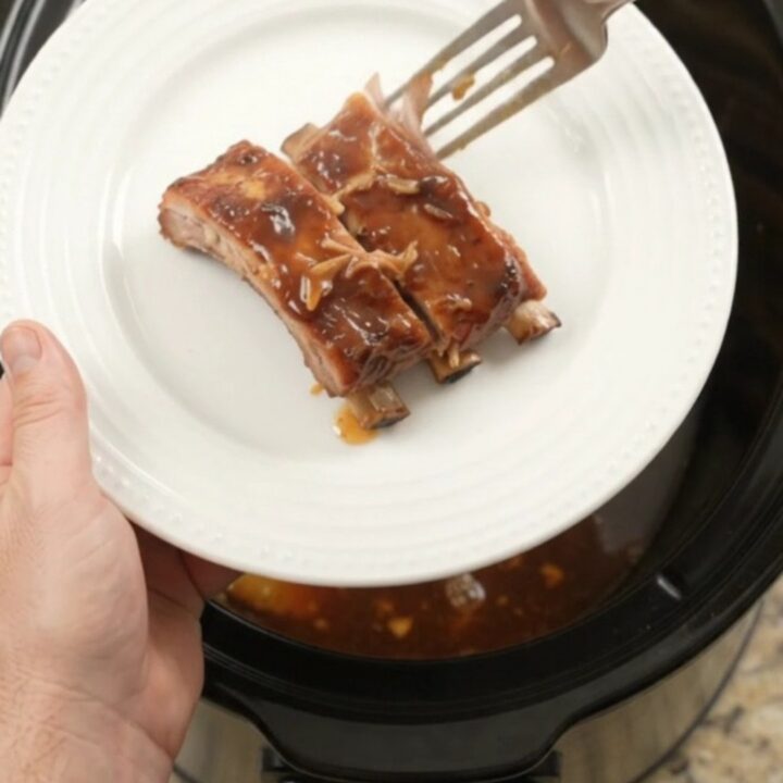A slow cooker filled with glazed spare ribs and caramelized pineapple rings