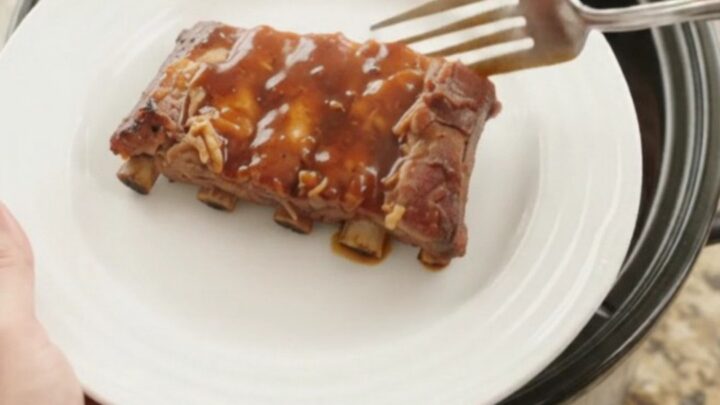 Glossy slow-cooked spare ribs in thick BBQ sauce with caramelized pineapple rings in a Crockpot
