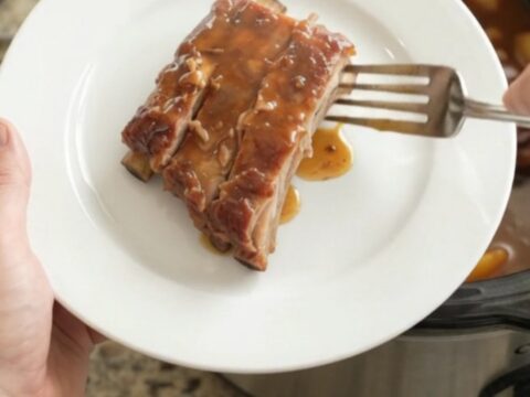 Slow-cooker spare ribs with peaches and maple bourbon barbecue sauce in a black crockpot