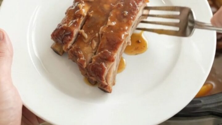 Slow-cooker spare ribs with peaches and maple bourbon barbecue sauce in a black crockpot