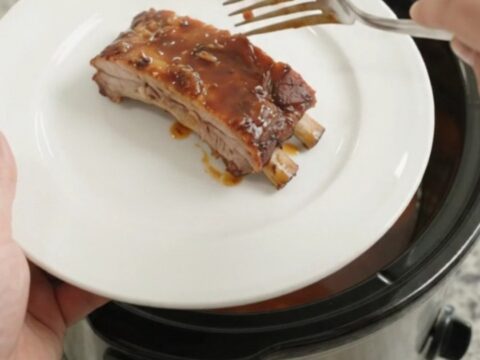 Slow-cooker spare ribs with peaches and BBQ sauce in a black crockpot