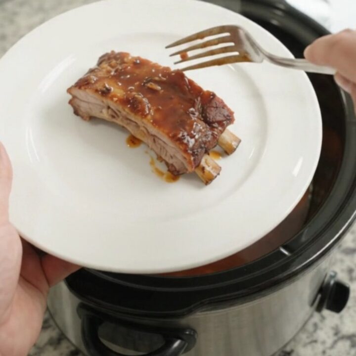 Slow-cooker spare ribs with peaches and BBQ sauce in a black crockpot
