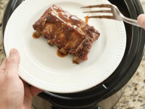 Slow cooker full of glazed spare ribs with peaches and sauce