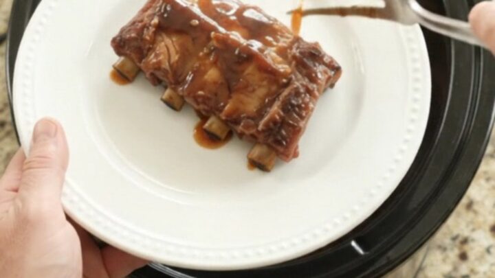 Slow cooker full of glazed spare ribs with peaches and sauce