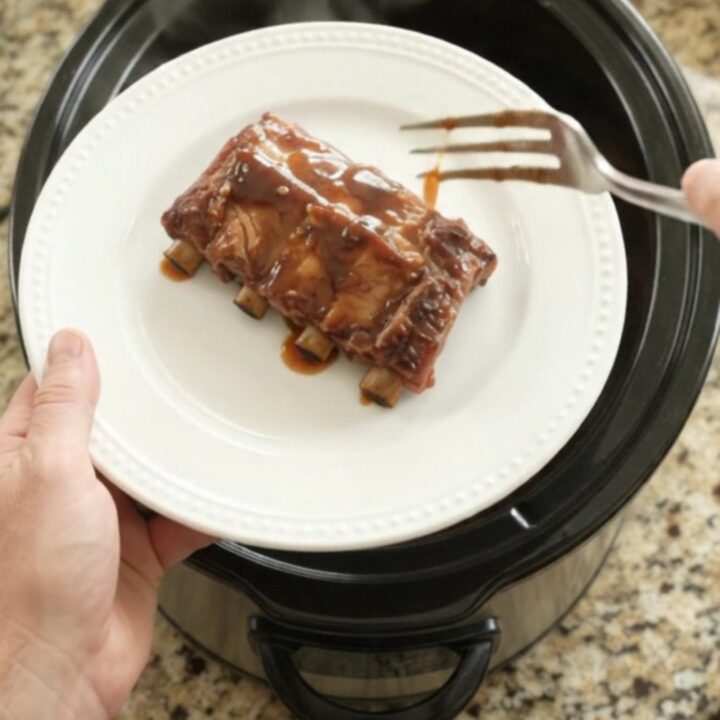 Slow cooker full of glazed spare ribs with peaches and sauce