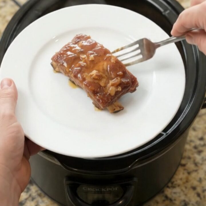 Slow-cooker spare ribs with pineapple rings in a glossy maple bourbon BBQ sauce, shown in the slow cooker.
