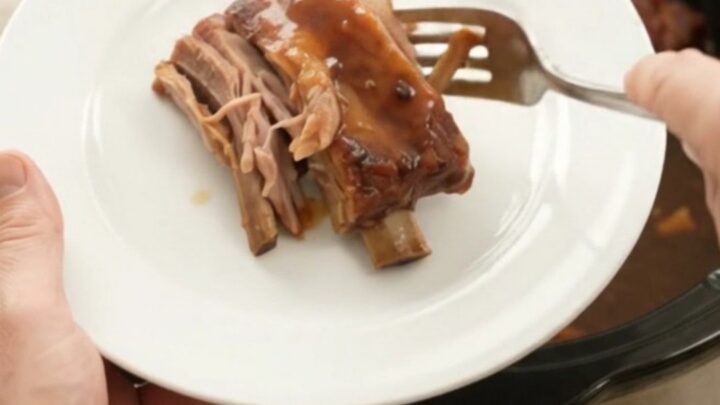 Sticky chipotle molasses spare ribs in a slow cooker with sauce bubbling