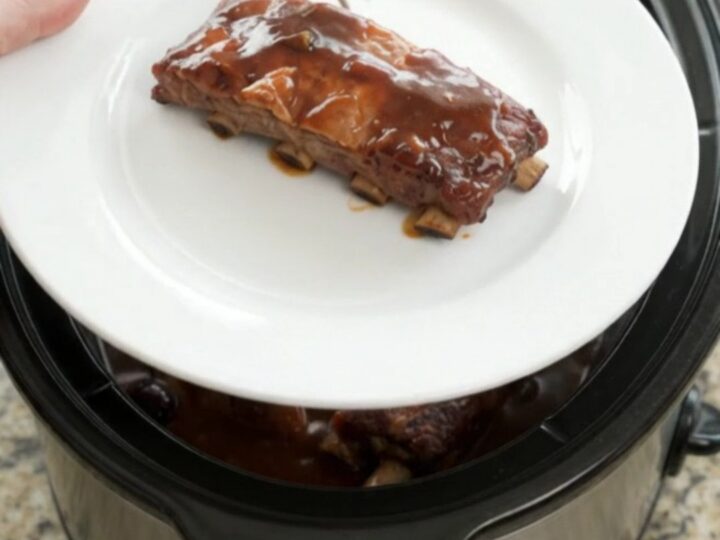Pull-apart pork spare ribs glazed with cherry cola BBQ sauce in a slow cooker.