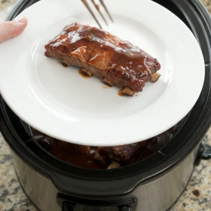 Pull-apart pork spare ribs glazed with cherry cola BBQ sauce in a slow cooker.