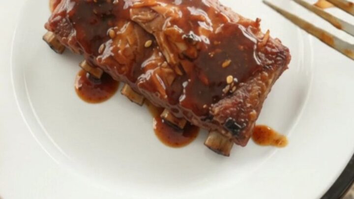 Slow-cooker spare ribs glazed with molasses BBQ sauce, garnished with fresh herbs