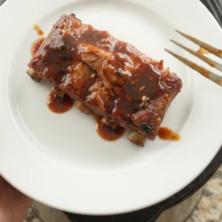 Slow-cooker spare ribs glazed with molasses BBQ sauce, garnished with fresh herbs