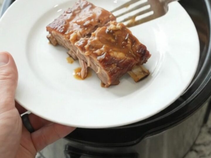 Slow cooker maple bourbon spare ribs glazed with sauce, garlic and rosemary