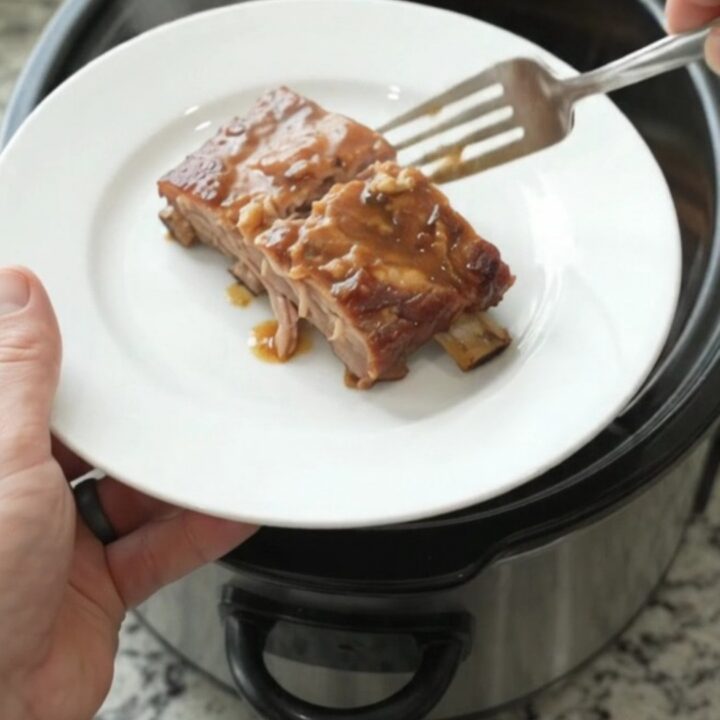 Slow cooker maple bourbon spare ribs glazed with sauce, garlic and rosemary