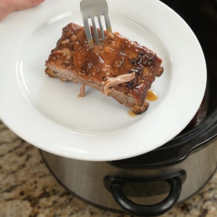 Slow-cooker spare ribs glazed with honey hickory barbecue sauce, garnished with fresh herbs