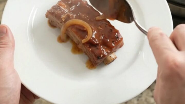 Fork-tender brown sugar BBQ country pork ribs glistening in a slow cooker with caramelized onions.