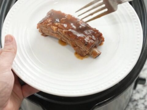Slow cooker brown sugar molasses country pork ribs with caramelized onions in a dark glossy sauce.