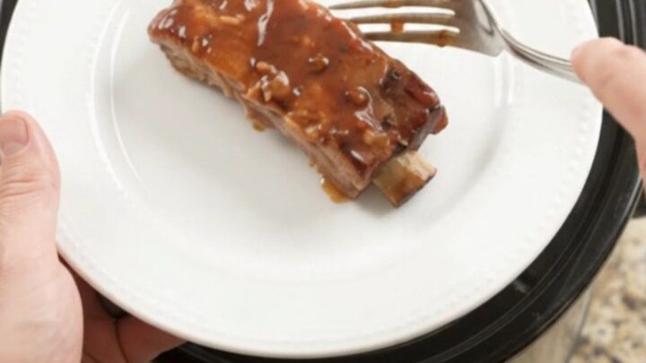 Glazed country-style pork ribs with apple slices in a slow cooker, topped with BBQ sauce.