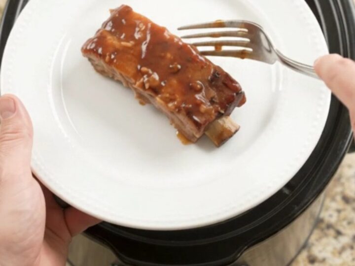 Glazed country-style pork ribs with apple slices in a slow cooker, topped with BBQ sauce.