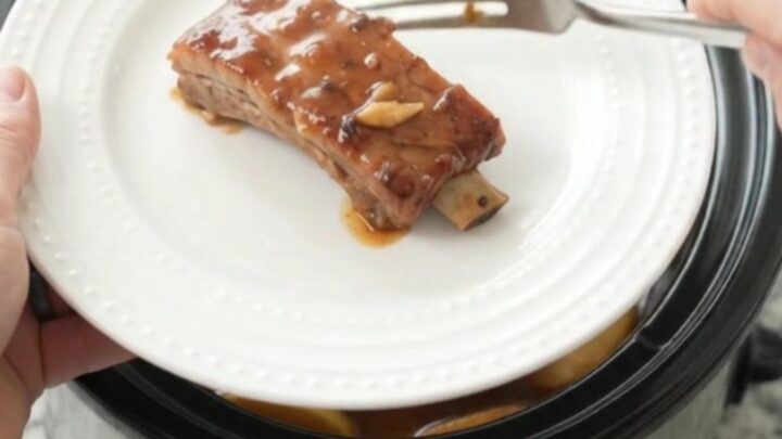 Slow cooker full of glazed pork ribs with soft apples and thick maple bourbon sauce