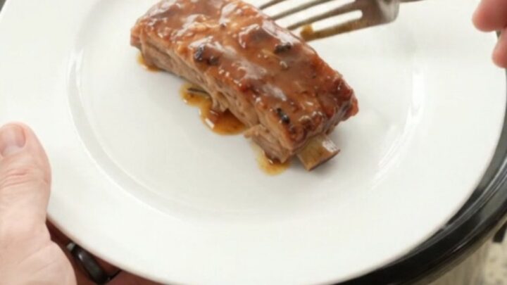 Slow-cooker country-style pork ribs glazed with honey-hickory BBQ sauce and surrounded by soft apple slices in a black
