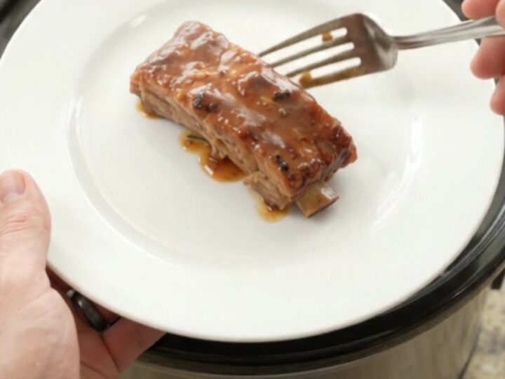 Slow-cooker country-style pork ribs glazed with honey-hickory BBQ sauce and surrounded by soft apple slices in a black