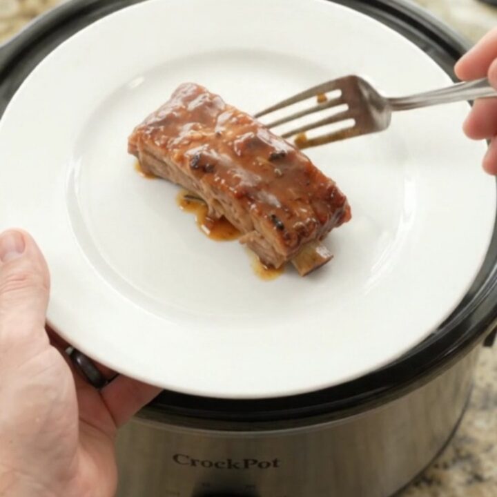 Slow-cooker country-style pork ribs glazed with honey-hickory BBQ sauce and surrounded by soft apple slices in a black