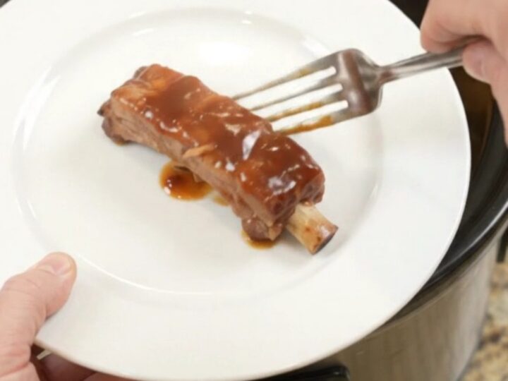 Slow cooker filled with glazed pork ribs, pineapple rings, and BBQ sauce