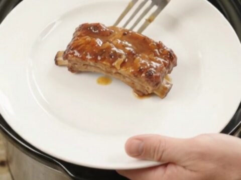 Glazed pork ribs with pineapple rings in a slow cooker, bubbling sauce