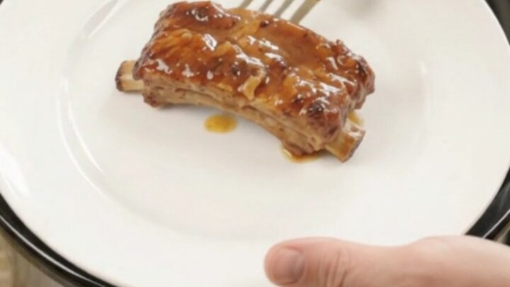 Glazed pork ribs with pineapple rings in a slow cooker, bubbling sauce