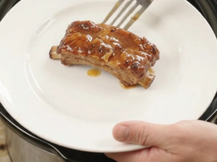 Glazed pork ribs with pineapple rings in a slow cooker, bubbling sauce