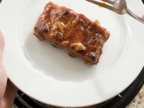 A slow cooker filled with glossy, fork-tender country-style pork ribs coated in a dark