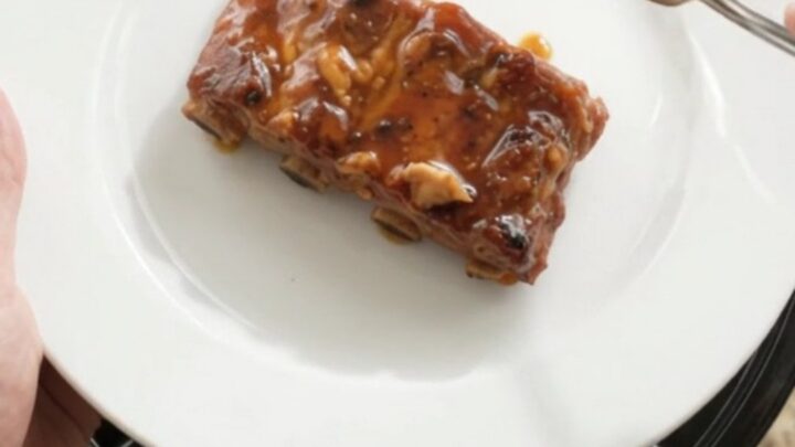 A slow cooker filled with glossy, fork-tender country-style pork ribs coated in a dark