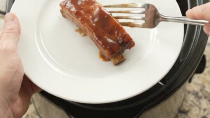 Glazed cherry cola BBQ country pork ribs in a slow cooker, bubbling in thick sauce