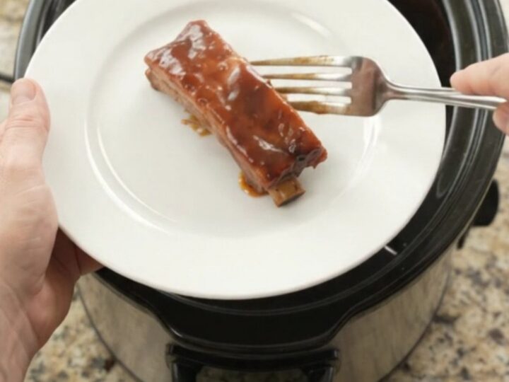 Glazed cherry cola BBQ country pork ribs in a slow cooker, bubbling in thick sauce
