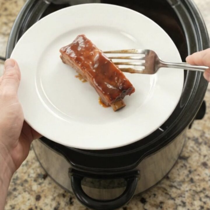 Glazed cherry cola BBQ country pork ribs in a slow cooker, bubbling in thick sauce