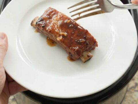 Slow-cooker country pork ribs glazed with molasses garlic sauce in a black crockpot