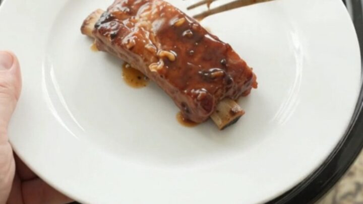 Slow-cooker country pork ribs glazed with molasses garlic sauce in a black crockpot