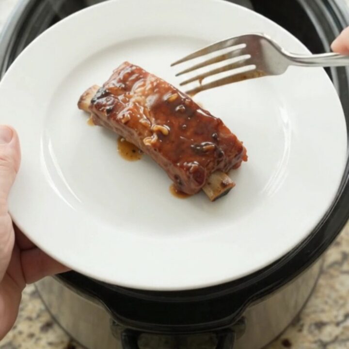 Slow-cooker country pork ribs glazed with molasses garlic sauce in a black crockpot