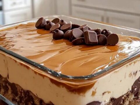 A clear glass dish filled with layers of chocolate cake, peanut butter cream, and caramel sauce.