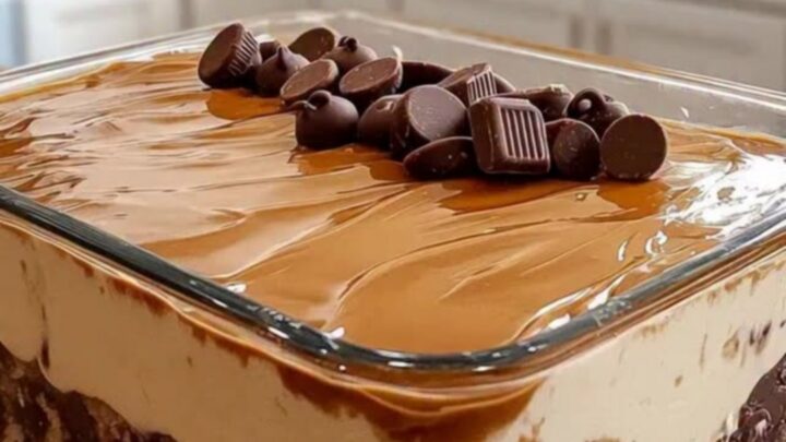 A clear glass dish filled with layers of chocolate cake, peanut butter cream, and caramel sauce.