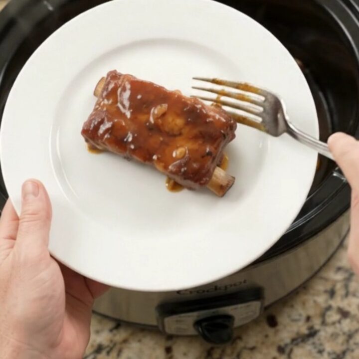 Slow cooker country-style pork ribs glazed with honey hickory BBQ sauce, topped with garlic cloves and rosemary