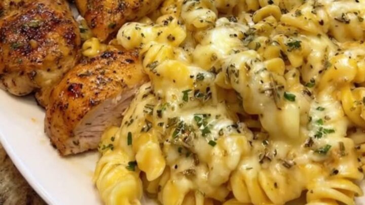 A close-up of creamy parmesan rotini with pieces of golden garlic butter chicken in a bowl.