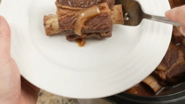 Brown Sugar BBQ Short Ribs in a slow cooker, glistening with sticky barbecue sauce and caramelized onions.
